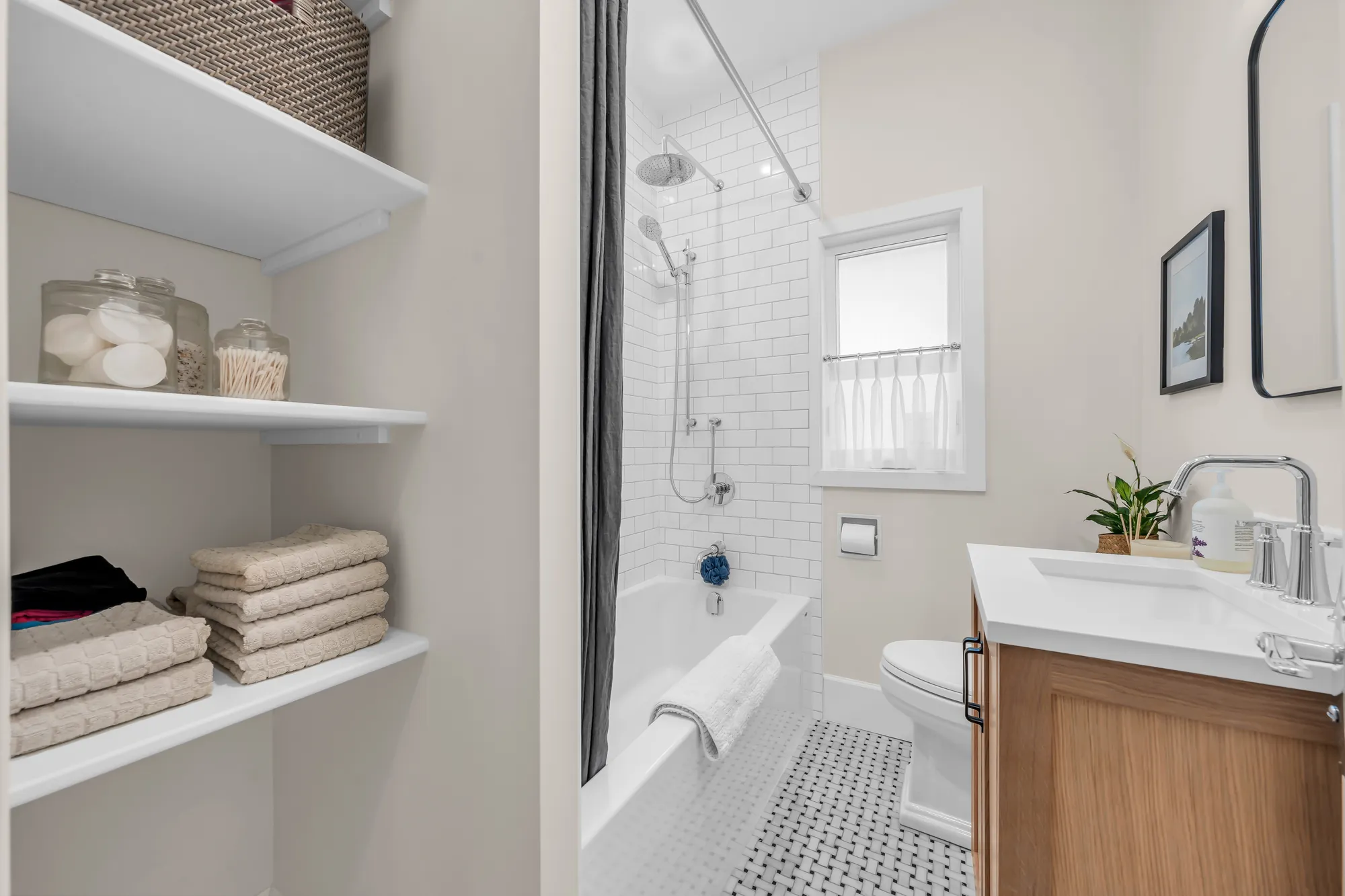 The bathroom: open shelves of towels beside the tub, the vanity and the window