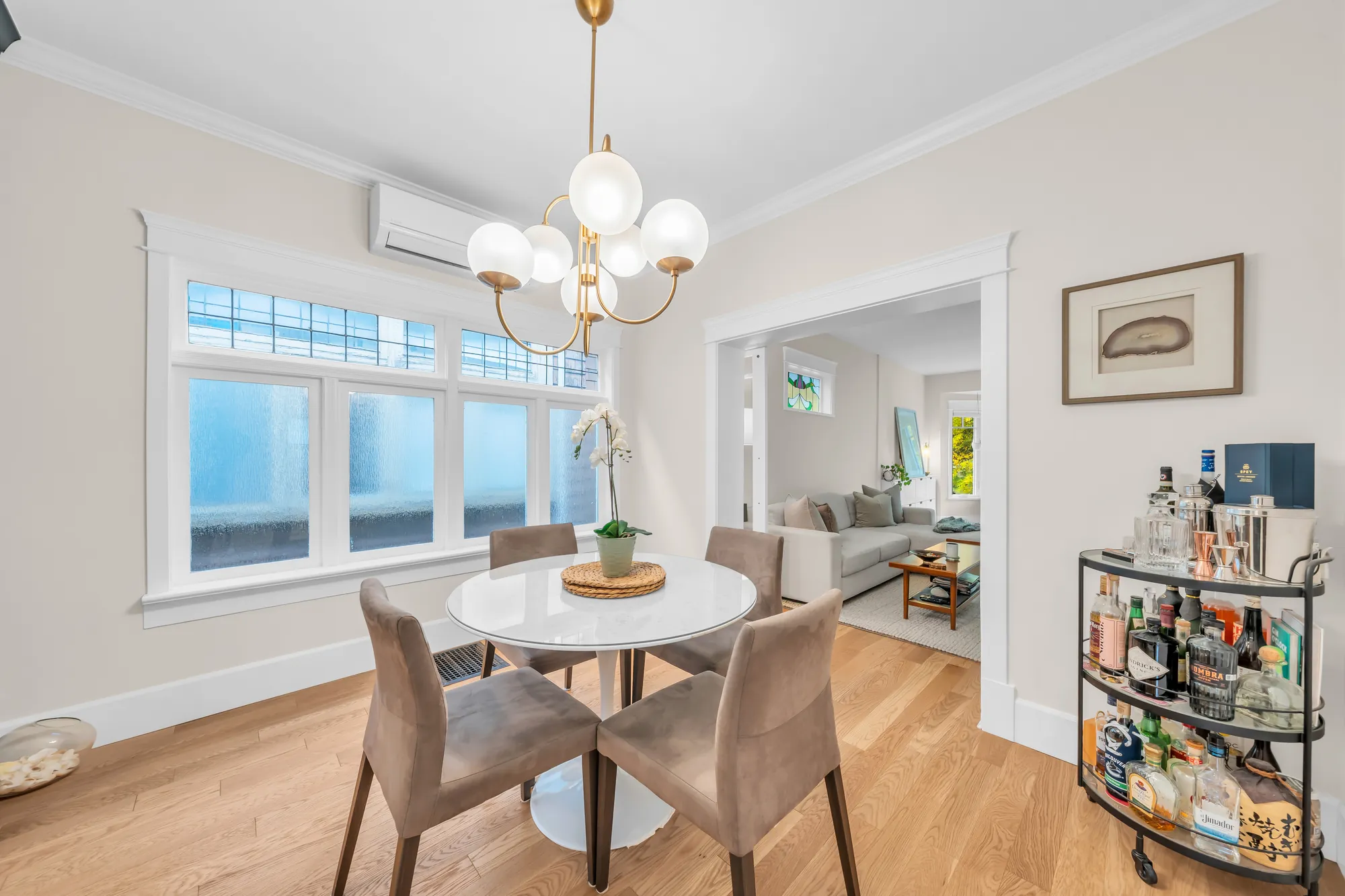 The dining room: windows with leaded upper panes, the round table, a bar cart