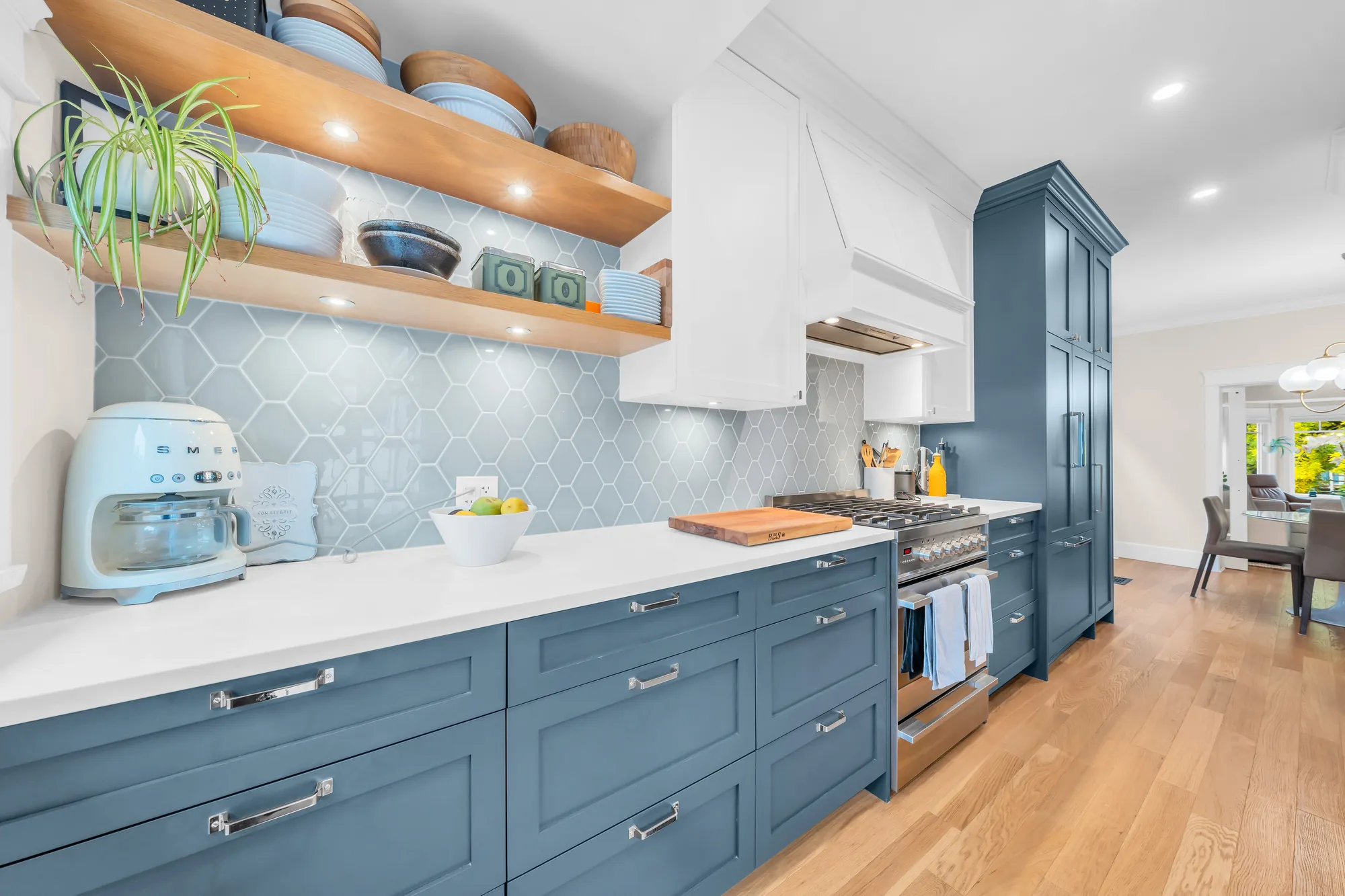 The counter below open wood shelves, the hexagon tile, the range and the hood