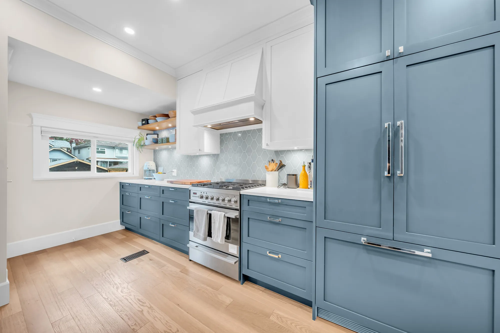 The kitchen toward the back window: the range and the hood, the panelled fridge and pantry at the right