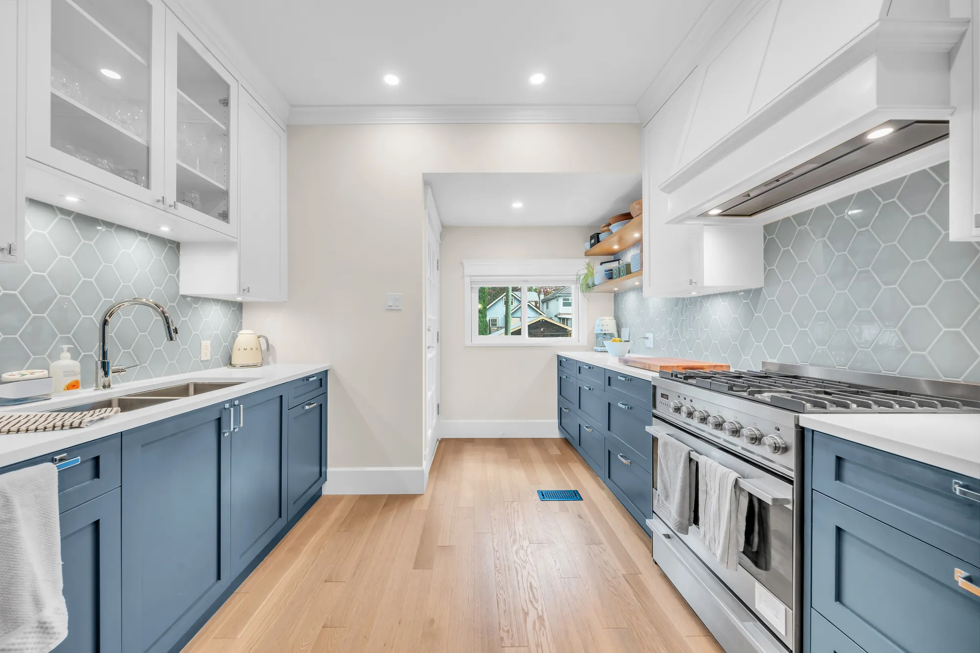 The sink with a gooseneck tap, the range across the aisle, the window at the far end