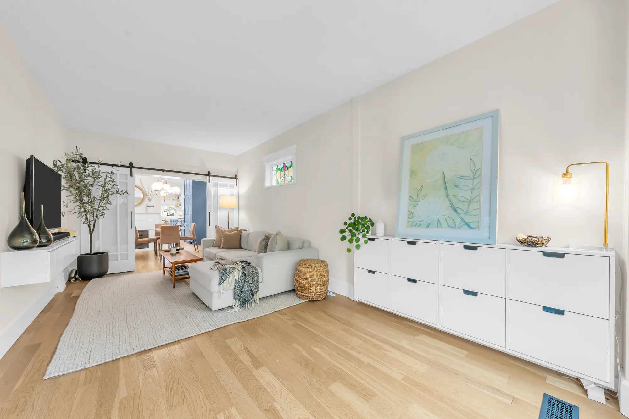 The living room: the white cabinet and a painting, a floor lamp, the barn doors to the dining room