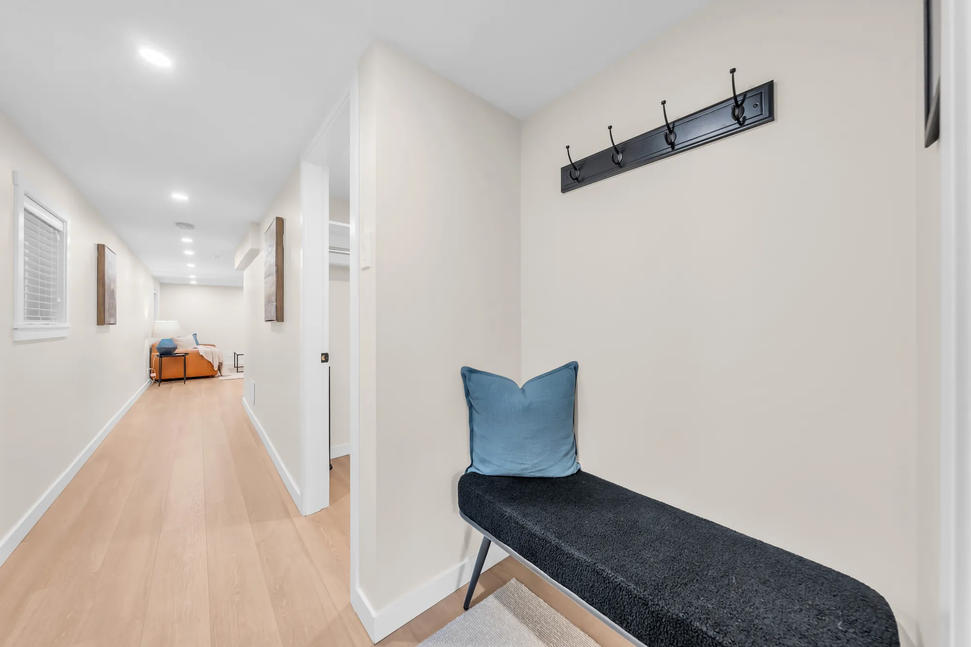 The long lower hall with a bench and coat hooks, the rooms off it