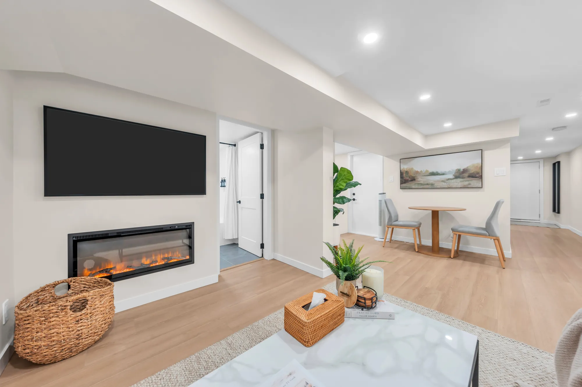 The lower living room toward the dining area and the hall, the fireplace and the television at the left